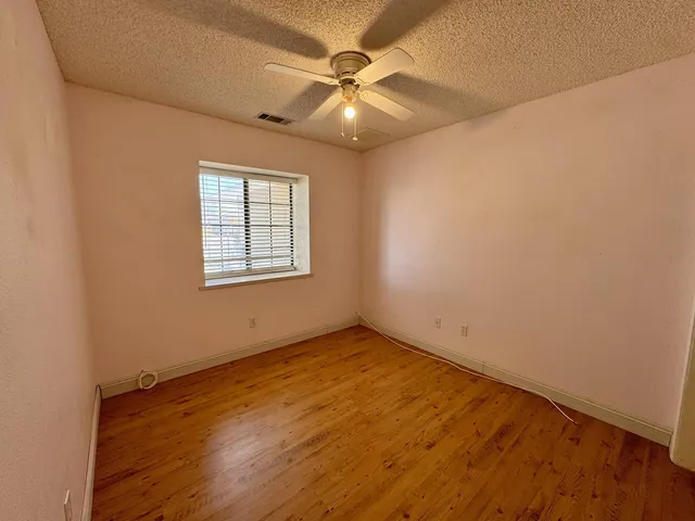 an empty room with a window and a ceiling fan