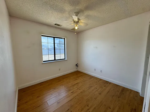 an empty room with a chandelier fan and windows