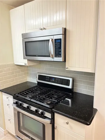 a living room with stainless steel appliances wooden floor and a fireplace