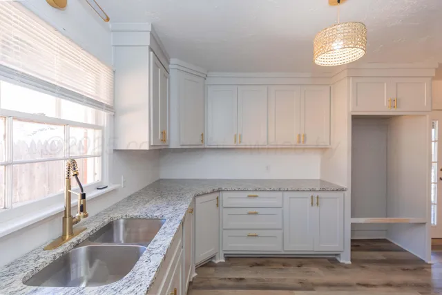 a kitchen with granite countertop a sink dishwasher and cabinets with wooden floor