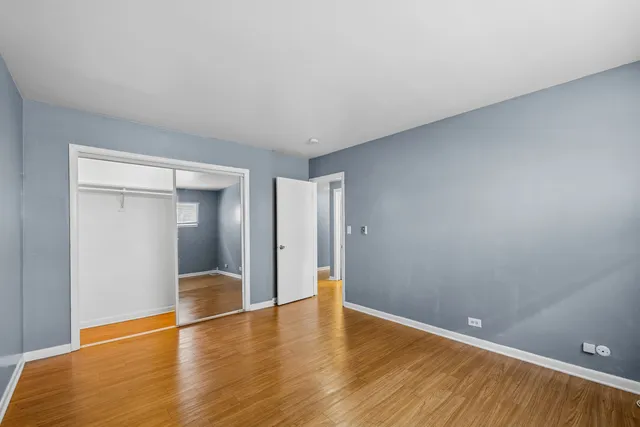 a view of an empty room with wooden floor and closet