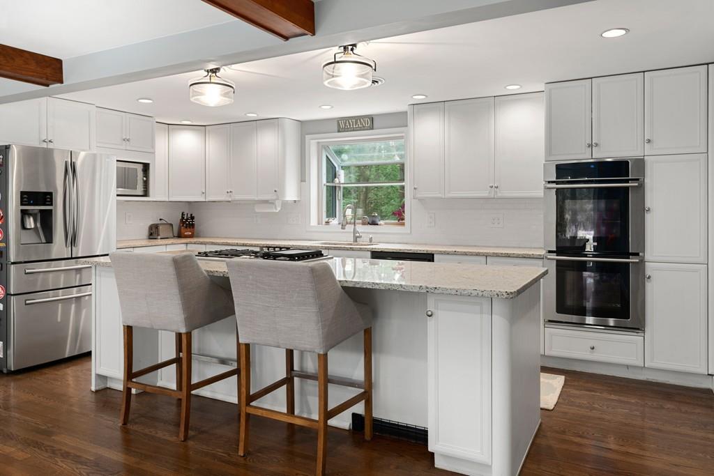 16 Standish Road Wayland, MA 01778 - Photo 8 of 22 a kitchen with stainless steel appliances granite countertop a sink a stove a refrigerator cabinets and a dining table with wooden floor