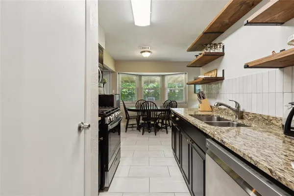 a kitchen with granite countertop sink stove and cabinets