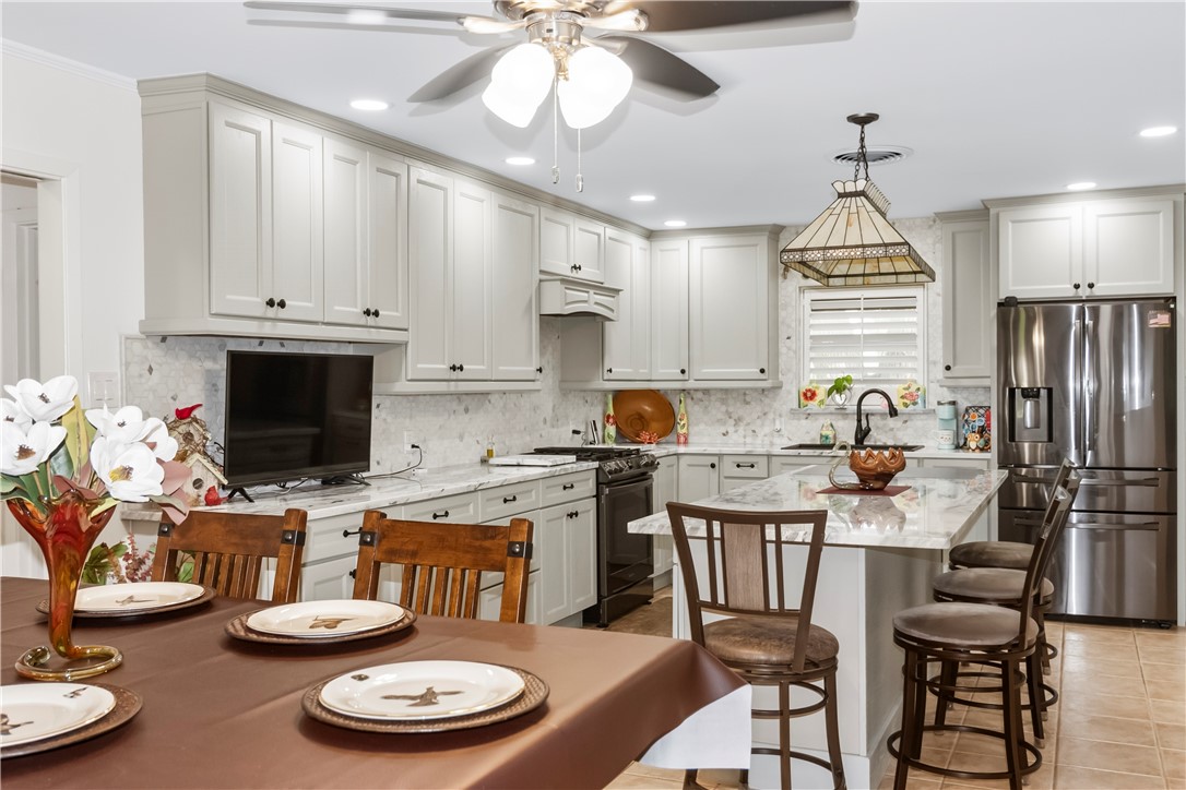 155 Harbor Circle Mathis, TX 78368 - Photo 11 of 40 a kitchen with stainless steel appliances kitchen island granite countertop a sink a stove a dining table and chairs