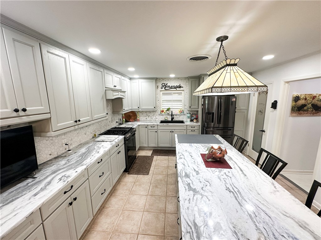 155 Harbor Circle Mathis, TX 78368 - Photo 13 of 40 a kitchen with stainless steel appliances granite countertop a stove top oven a sink dishwasher and a fireplace with wooden floor