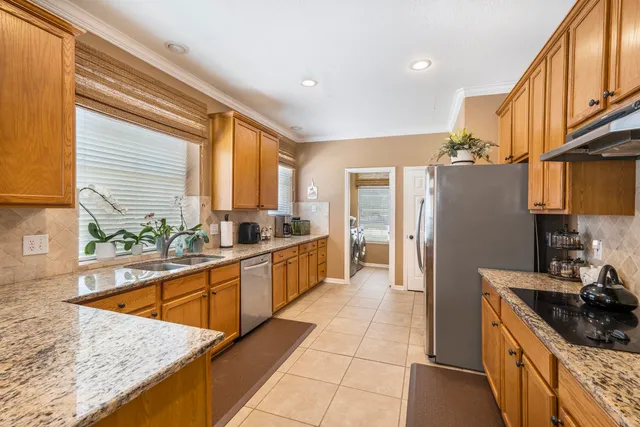 a kitchen with stainless steel appliances granite countertop a sink a stove and a refrigerator
