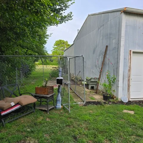 a view of a backyard with chairs potted plants and a large tree