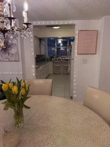 a living room with stainless steel appliances furniture a rug and a kitchen view