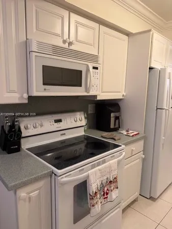 a kitchen with granite countertop white cabinets and white stainless steel appliances