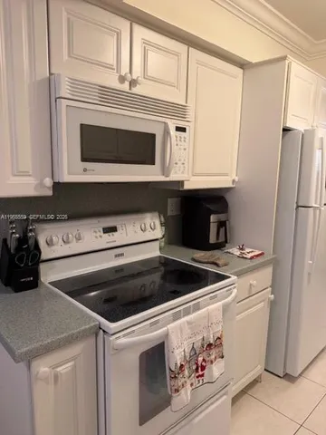 a kitchen with granite countertop white cabinets and white stainless steel appliances