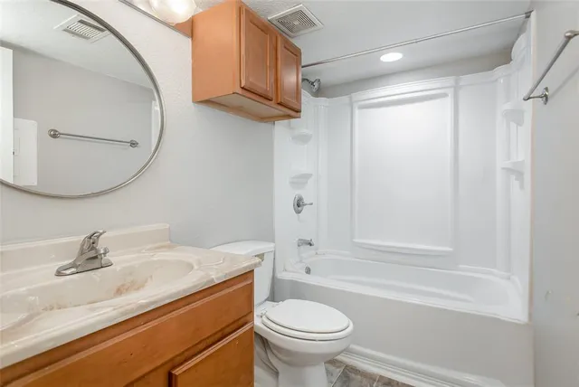 an empty room with chandelier fan and windows