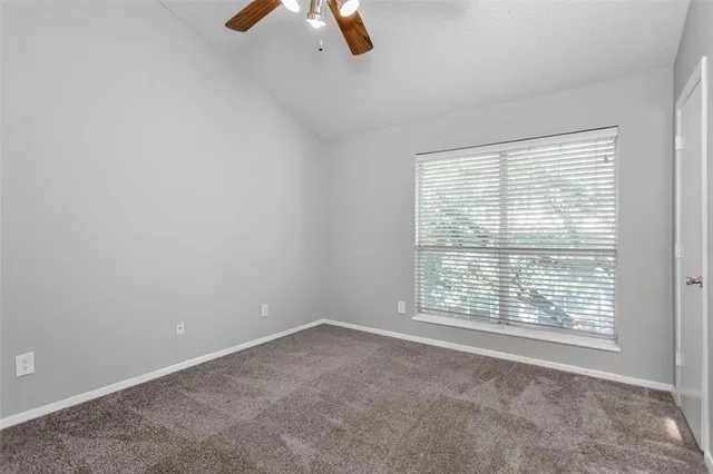 an empty room with closet and a ceiling fan