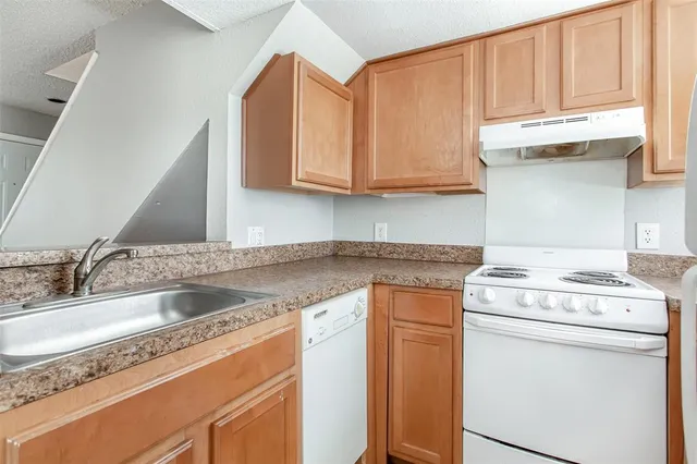 a kitchen with granite countertop a sink a stove and cabinets
