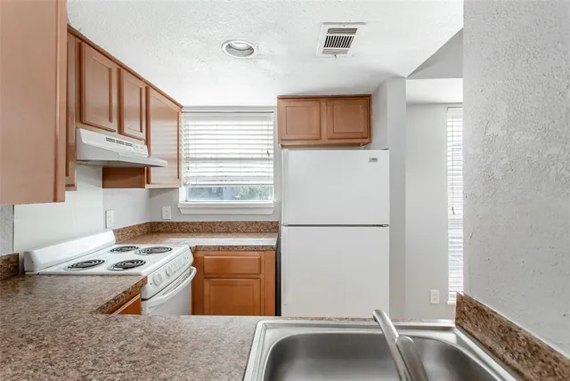 a kitchen with a refrigerator and a stove top oven