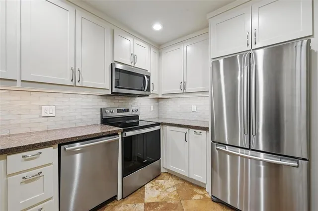 a kitchen with stainless steel appliances granite countertop a refrigerator stove a sink and a microwave