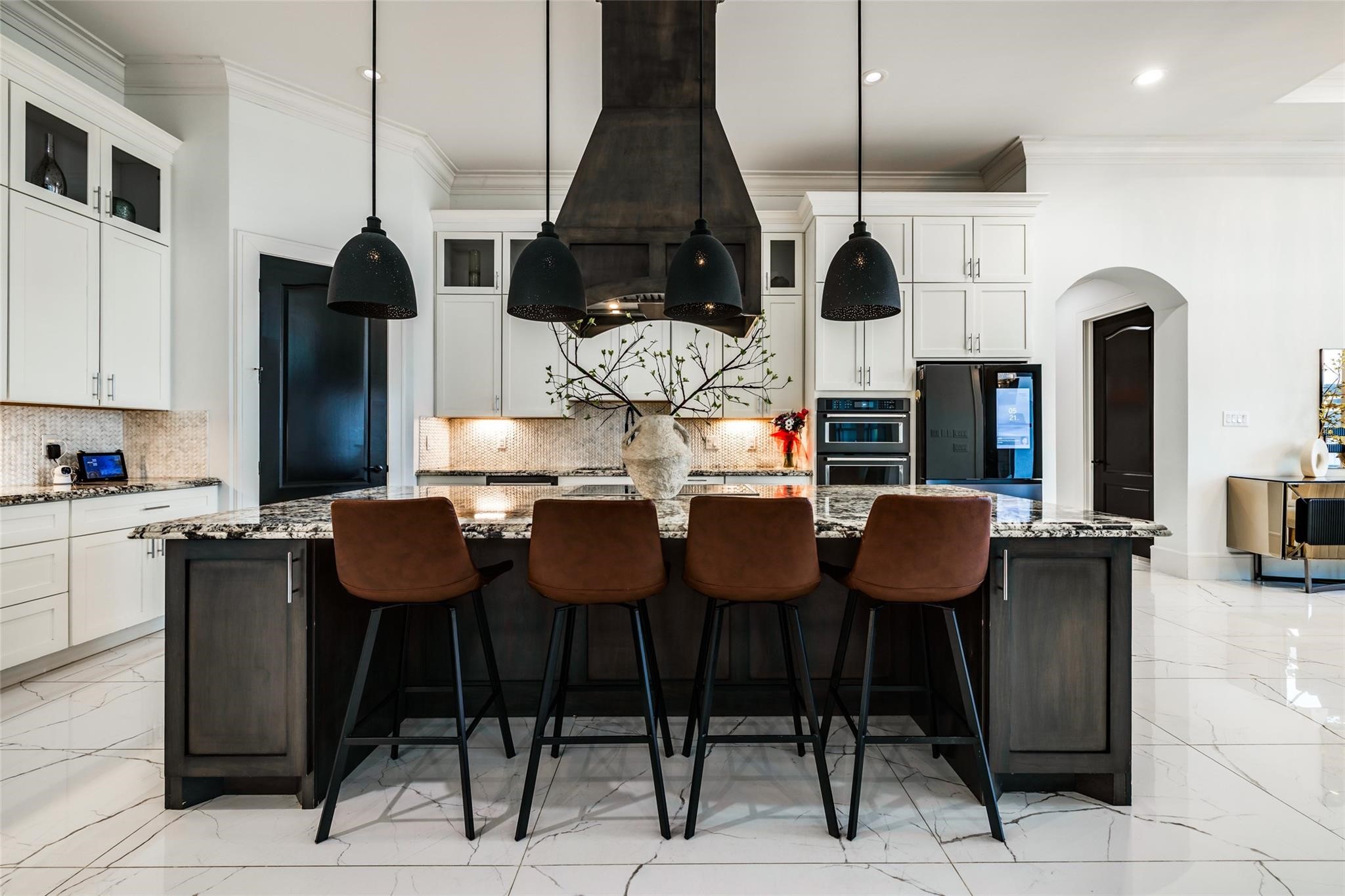 4821 Walters Road Richmond, TX 77469 - Photo 26 of 50 his designer gourmet kitchen makes a bold statement with soaring custom cabinetry, dramatic ceiling-height finishes, and an oversized waterfall island perfect for entertaining. Featuring premium stainless steel appliances, elegant pendant lighting, marble-style flooring, and rich contrasting accents, the space blends timeless sophistication with modern functionality. The open-concept layout, expansive prep areas, built-in wine storage, and abundant natural light create a luxurious culinary experience