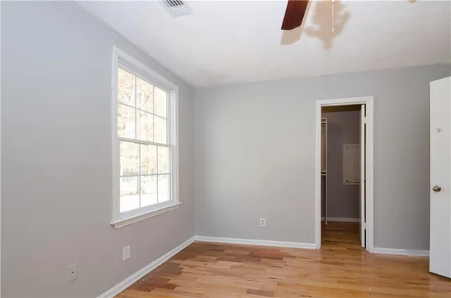 a view of an empty room with wooden floor and closet