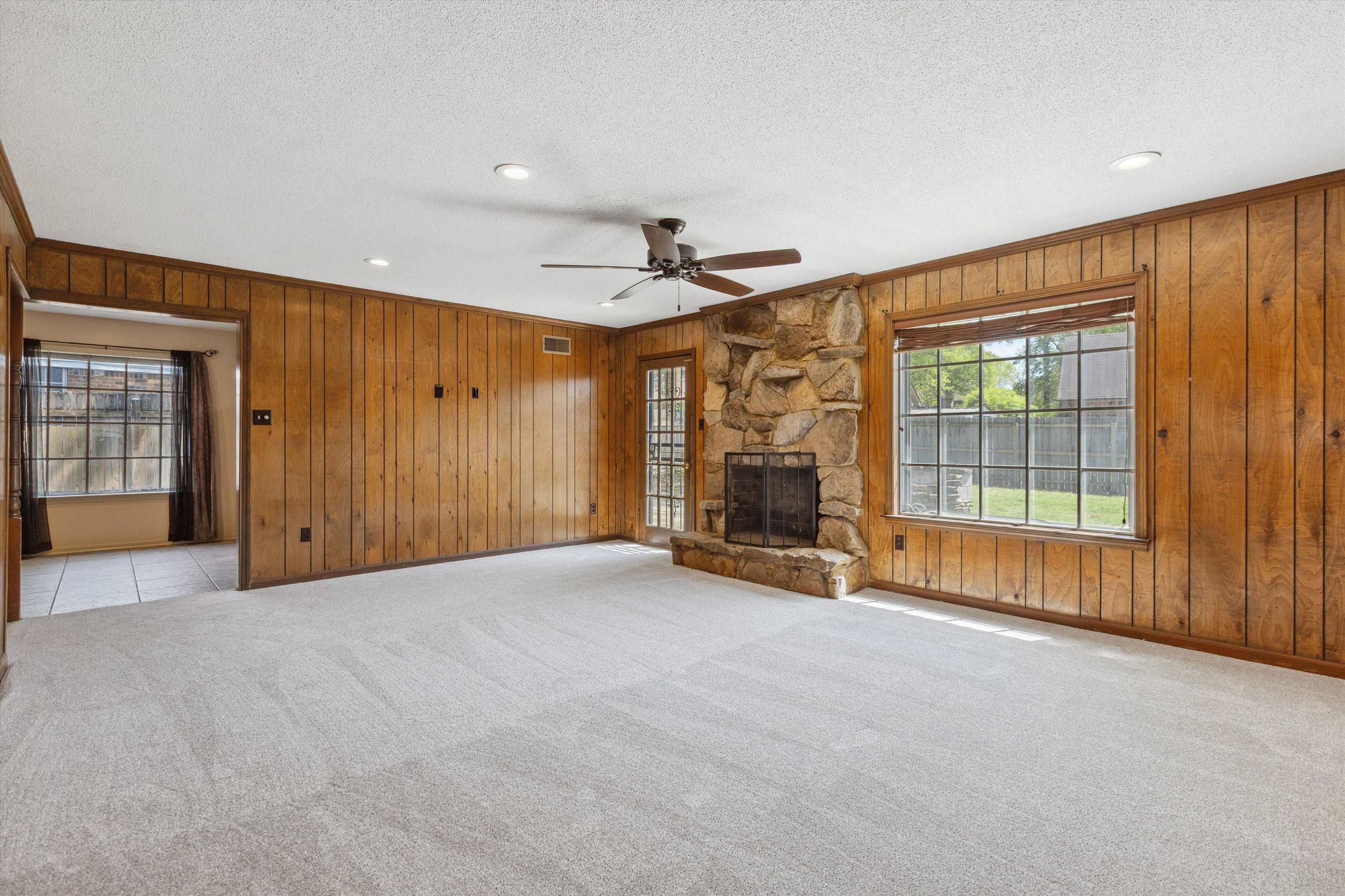 5747 Bartlett Woods Drive Bartlett, TN 38134 - Photo 12 of 28 Unfurnished living room with crown molding, wood walls, light colored carpet, and a ceiling fan