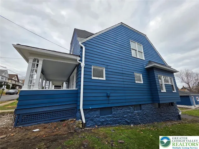a backyard of a house with wooden fence and large trees