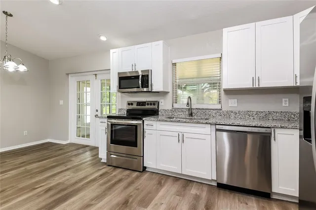 a kitchen with granite countertop a stove a sink and a microwave