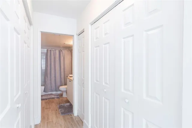 a view of a hallway with wooden floor and a bathroom