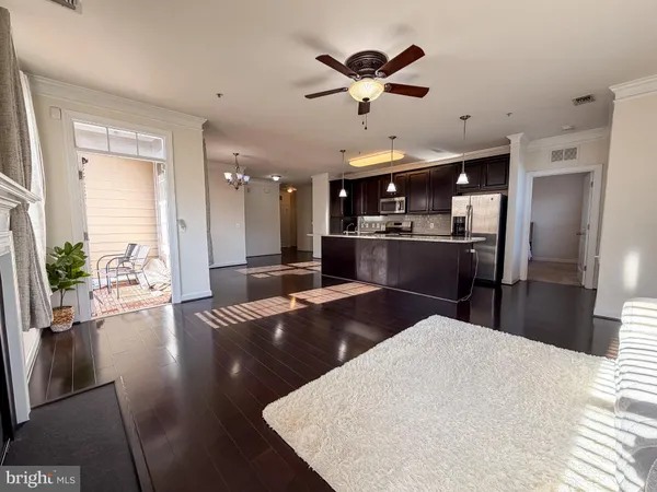a kitchen with stainless steel appliances kitchen island granite countertop a refrigerator a sink a stove and a dining table with wooden floor