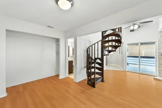 a view of a room with wooden floor and a ceiling fan