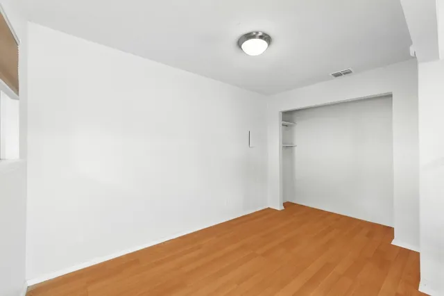 a view of an empty room with stairs and wooden floor