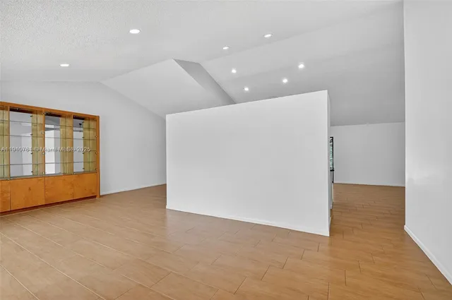 a view of an empty room with wooden floor and windows