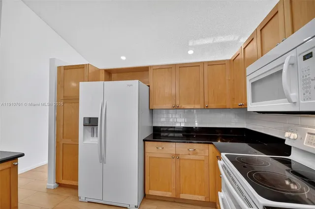 a kitchen with stainless steel appliances granite countertop a sink a refrigerator and a stove