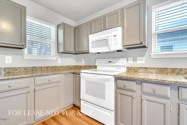 a kitchen with granite countertop white cabinets and white appliances