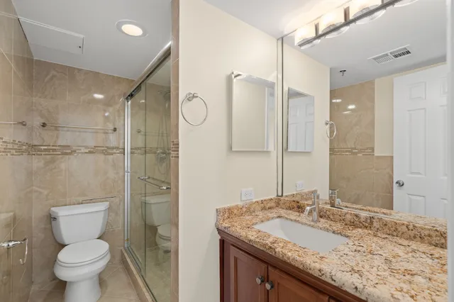 a bathroom with a granite countertop sink toilet and shower