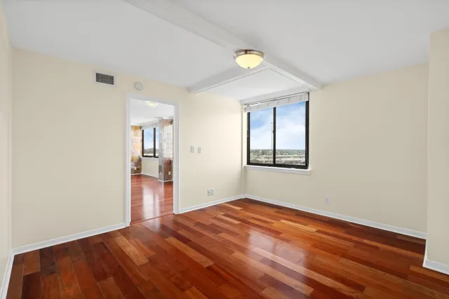 a view of empty room with wooden floor and fan