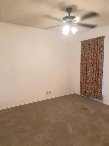 a view of an empty room and chandelier fan