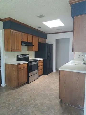 a kitchen with stainless steel appliances a stove a sink a microwave a refrigerator and cabinets