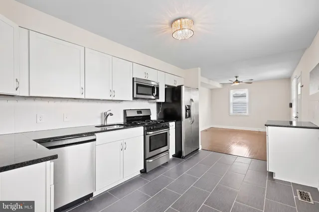 a kitchen with granite countertop a sink stainless steel appliances and white cabinets