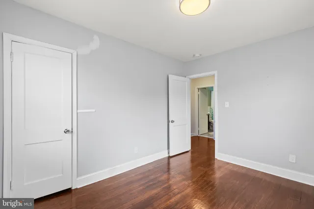 a view of an empty room with wooden floor and window