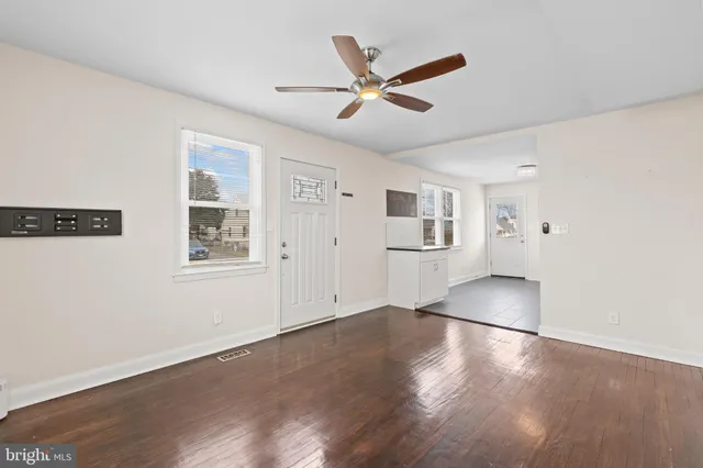 a view of a livingroom with wooden floor ceiling fan and windows