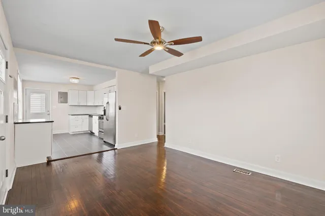 a view of a kitchen with wooden floor a ceiling fan and stainless steel appliances