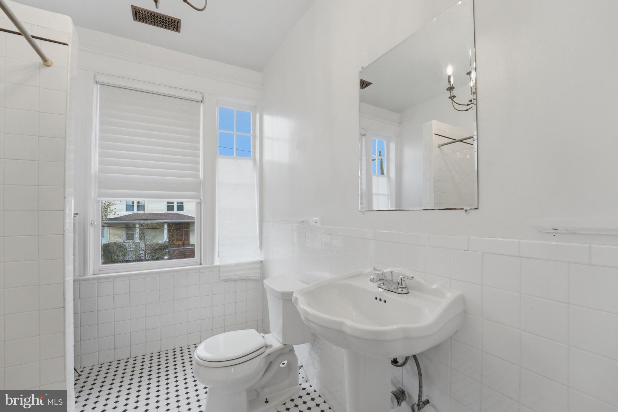1310 Emerson Street Northwest Washington, DC 20011 - Photo 19 of 38 a bathroom with a sink a toilet a mirror and shower curtain