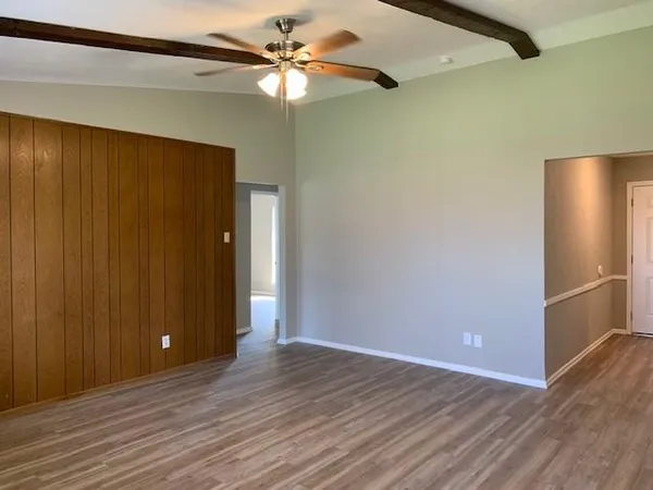 an empty room with wooden floor closet and windows