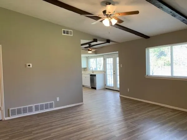 a view of an empty room with window and wooden floor