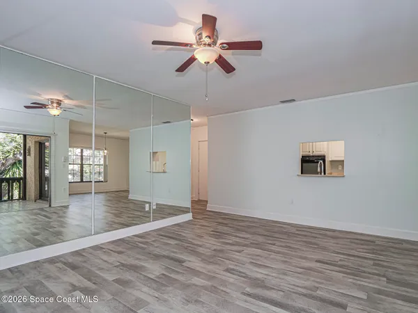 a view of an empty room with window and wooden floor