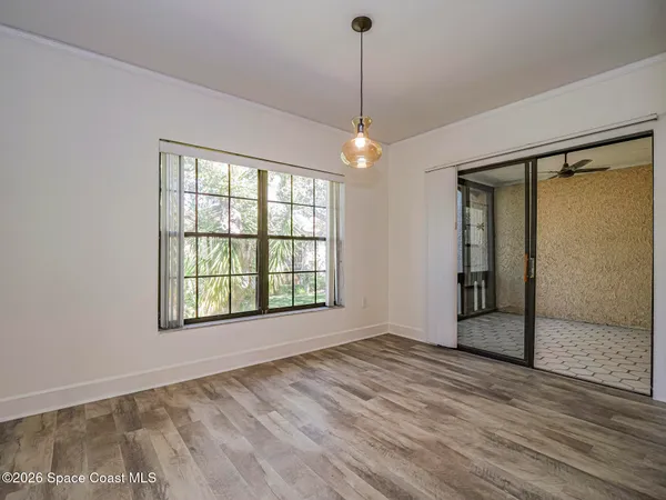 a view of an empty room with window and chandelier fan