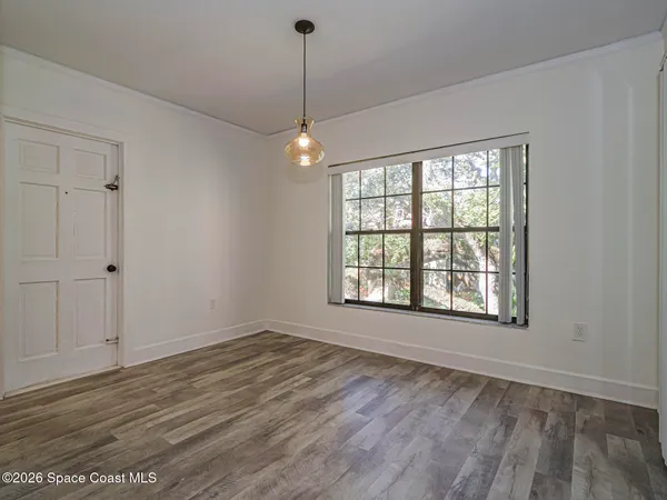 a view of an empty room with a window and wooden floor