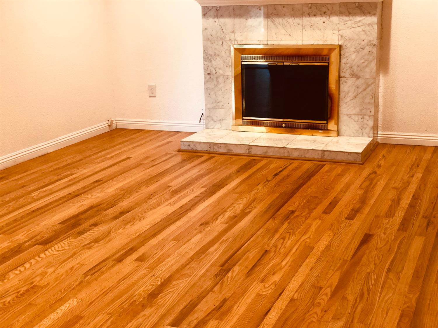a view of empty room with wooden floor and a fireplace