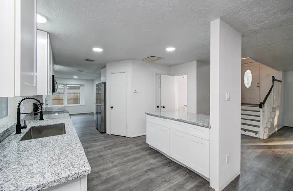 a kitchen with granite countertop a sink and a stove top oven with wooden floor