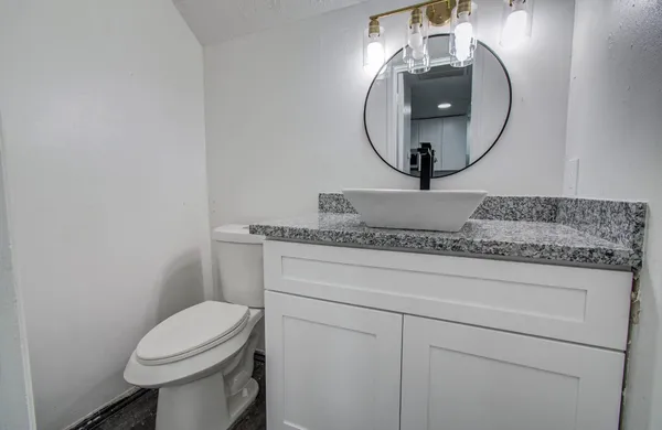 a bathroom with a toilet sink vanity and mirror