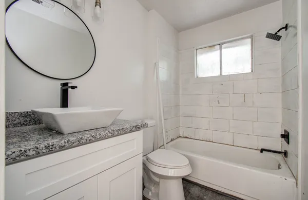 a bathroom with a granite countertop toilet sink and mirror