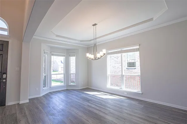 a view of an empty room with wooden floor and windows